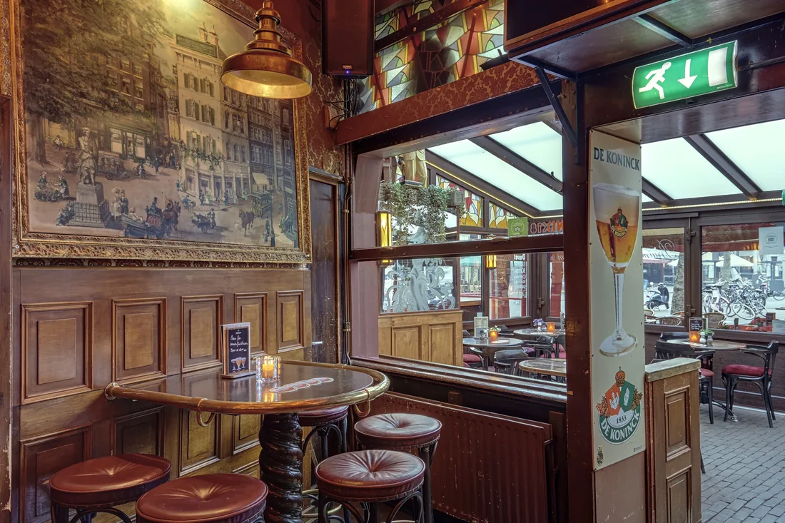 A cosy corner with a painting, copper lamp and bar stools